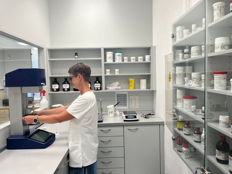 Apothekenmitarbeiterin der Lonetal Apotheke bei der Herstellung von Rezepturarzneimitteln im modernen Labor mit Labormaschine, Waage und Wirkstoffbehä
